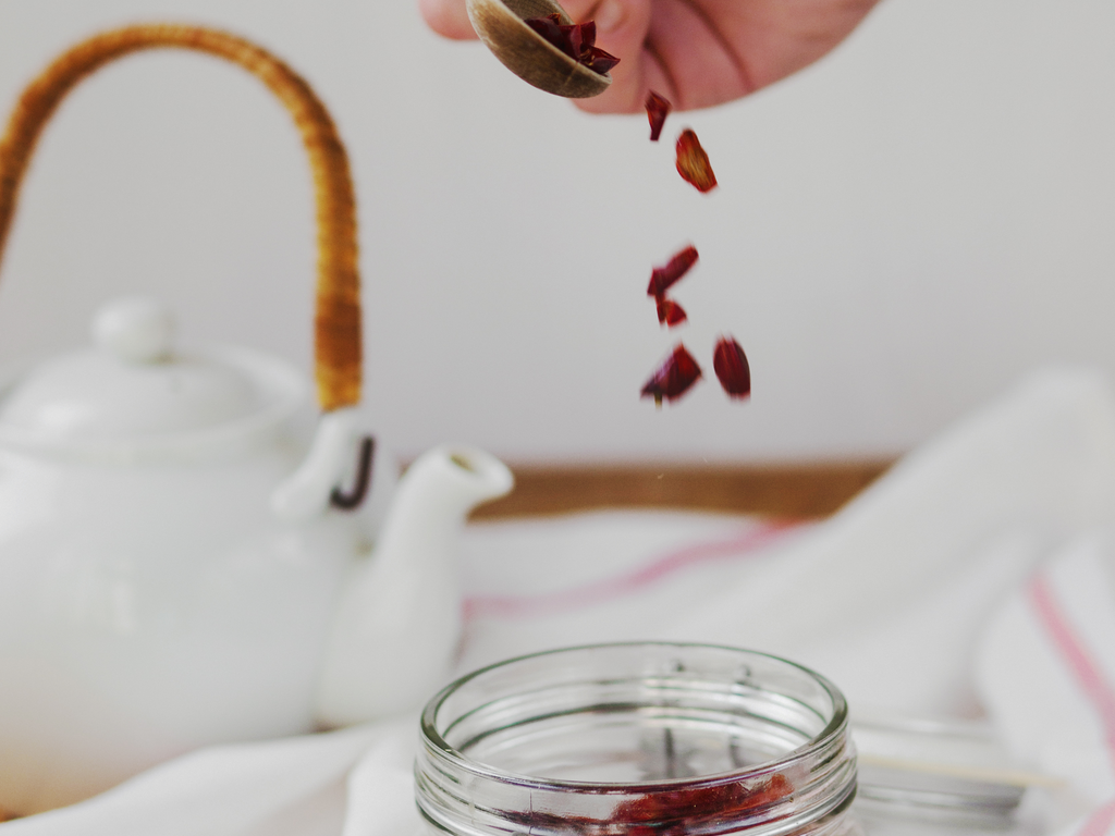 Crimson cleansing barberry detox tea in a glass cup with whole dried berries and mint